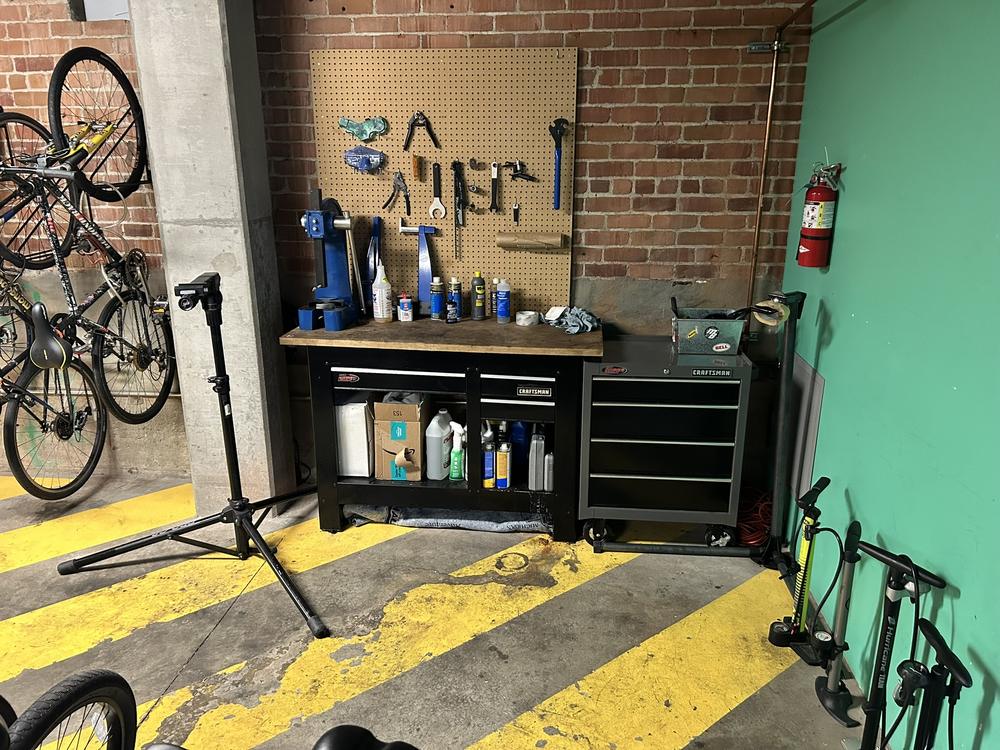 The Bicycle Kitchen — community repair bench with tools, work stand, and floor pumps in the garage