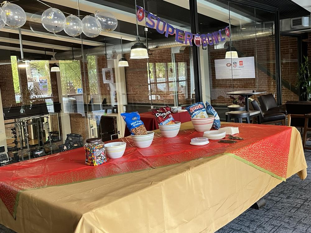 Super Bowl watch party setup in the lounge — snack table, balloons, and banner